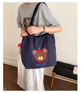 Detail of navy blue tote bag featuring 3D bear embroidery and drawstring closure