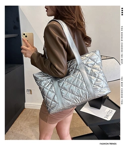 Photo de rue d'un grand sac cabas matelassé argenté porté à l'épaule pour femme
