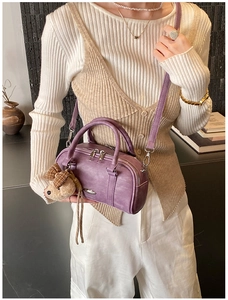 Detail of purple Boston cylinder handbag with vintage texture and cute bear pendant