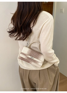 Schicke Handtasche mit Krokodilmuster und Kettenriemen in einem minimalistischen Outfit