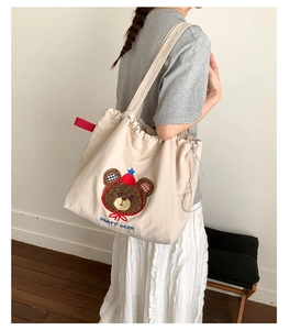 Detail of embroidered party bear motif on a beige canvas tote bag for daily use