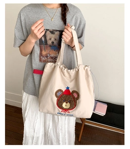 Detailed close-up of party bear embroidery and drawstring closure on canvas tote bag