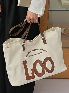 Minimalist cream canvas tote bag with brown leather handles and art letter print
