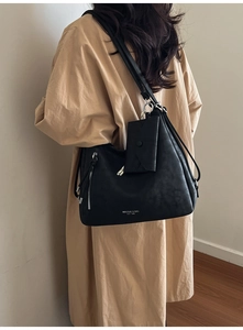Détail d'un grand sac hobo en cuir noir avec zip latéral et logo de marque sur le bas