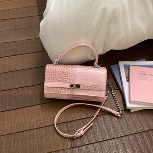 Nahaufnahme der rosa Krokodil-Textur mit silbernem Metalldrehverschluss an der Handtasche