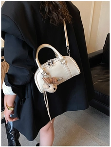 Detail of cream white leather boston bag with silver hardware and bear charm
