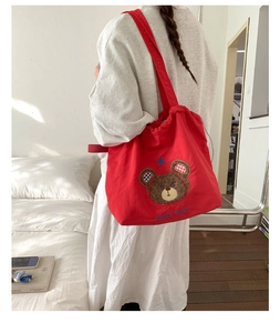 Detail of red canvas tote bag showing bear embroidery and drawstring closure