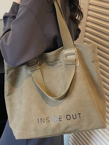 Olive green large canvas tote bag with INSIDE OUT print shown on shoulder