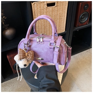 Detail view of purple faux leather pillow bag featuring a cute bear plush charm and hardware