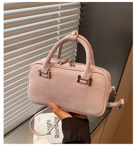 Detail of pink faux suede box bag featuring embossed logo and gold metal hardware