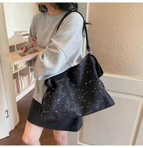 Gros plan sur un sac cabas noir à motif étoiles avec un charmant pendentif en étoile