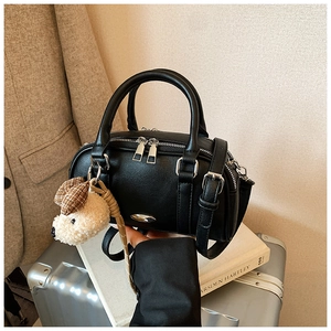 Black pebbled leather Boston bag detail with plush puppy charm and silver hardware accents
