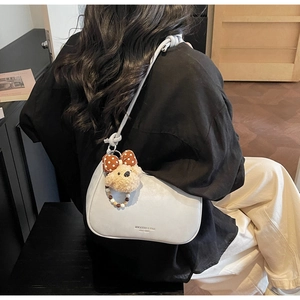 Detail view of smooth leather underarm bag with cute bear charm and knotted strap