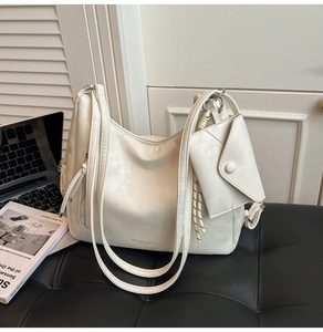 Vue détaillée du grand sac cabas en cuir crème avec pochette enveloppe sur un banc noir