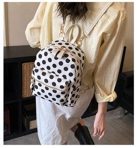 Close-up of stylish mini polka dot canvas backpack featuring white straps and gold hardware