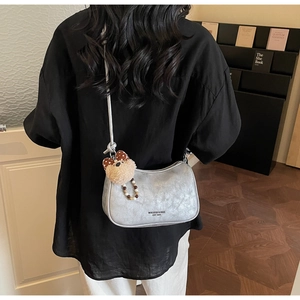 Silver vintage underarm bag with teddy bear charm and beaded chain on a model