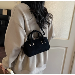 Detail showing back view of black matte leather handbag with adjustable crossbody strap