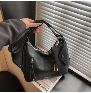 Détail du sac hobo en cuir noir mat avec poche zippée et pochette enveloppe assortie