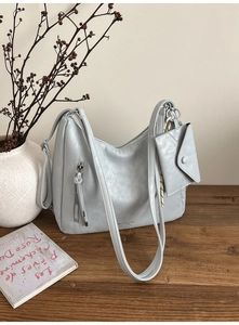 Gros plan d'un sac cabas vintage bleu-gris avec petite pochette sur bureau en bois