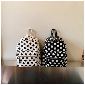Detailed close-up of polka dot pattern backpacks with gold zippers in black and white