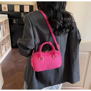 Model wearing a rose red suede crossbody bag over a stylish dark grey blazer jacket