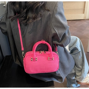 Detail view of pink textured leather crossbody bag with logo and gold-tone metal hardware