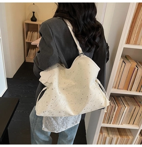 Détail d'un grand sac cabas blanc à motif étoiles avec cordons latéraux sur l'épaule