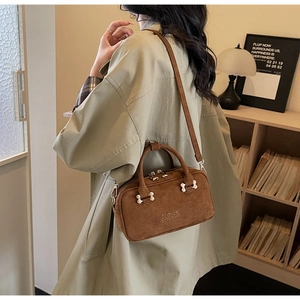 Detail of a brown suede Boston handbag with Rosy Doderia brand embossing and fine shoulder strap