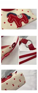 Detail of canvas bag with red polka dots, horse embroidery, and red leather strap