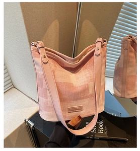 Vue détaillée du sac seau rose en tissu texturé avec sa bandoulière élégante en cuir