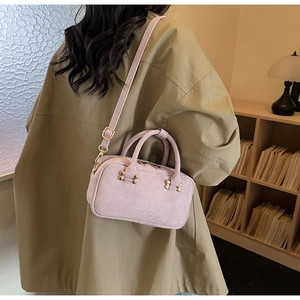 Detail of light purple suede shoulder bag featuring Rosy Gardenia logo and gold hardware