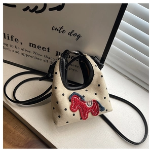 Detailed macro view of beige canvas mini bag featuring black polka dots and pony embroidery