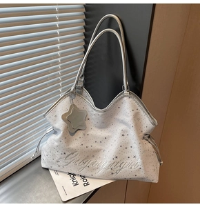 Détail du sac cabas argenté à imprimé étoiles avec breloque et broderie chic