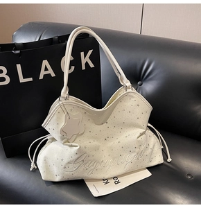 Détail du sac cabas blanc avec imprimés étoiles argentées et broderie calligraphiée