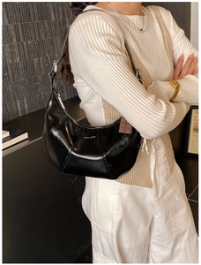 Detailed view of black patent leather hobo bag with white Love & Desire text