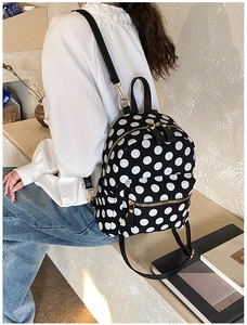 Detailed macro view of the black polka dot backpack with golden metal zippers and hardware