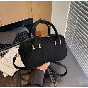 Close-up of black matte handbag on desk featuring unique bone-shaped metal buckles