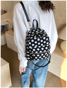 Detailed view of polka dot backpack with gold metal zippers and synthetic leather straps