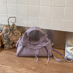 Detail view of lavender bow handbag with circular handle and elegant leather texture