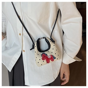 Detailed view of canvas mini bag with black polka dots and red pony embroidery on white shirt