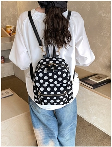 Rear view of a model wearing the mini black and white polka dot backpack on one shoulder