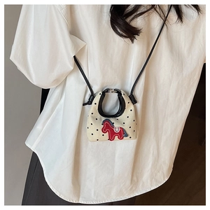 Detail of mini canvas crossbody bag with black polka dots and red pony embroidery
