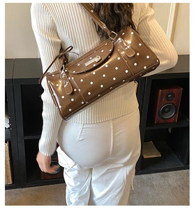 Sac baguette marron à pois avec rivets vintage porté par un mannequin dans un studio