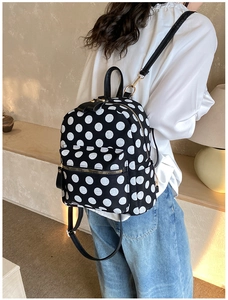 Close-up of black polka dot backpack showing gold hardware and canvas texture