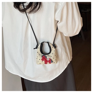Detail of mini cream crossbody bag with black polka dots and red pony patch embroidery