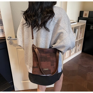 Détail du sac seau à motifs géométriques marron rouge avec bandoulière et finitions dorées