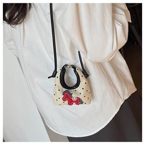 Close-up of mini polka dot canvas crossbody bag with red horse embroidery detail