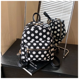 Detailed macro view of black polka dot canvas backpack with gold zipper on a glossy surface