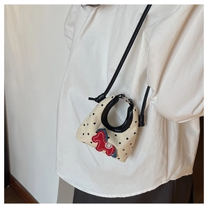 Detail view of mini knit crossbody bag with black polka dots and embroidered pony patch