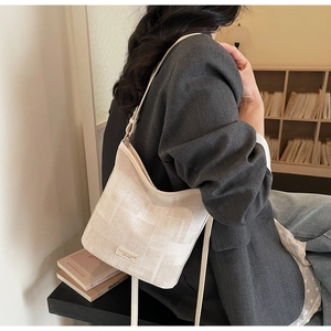 Détail d'un sac seau minimaliste en toile crème avec bandoulière en cuir réglable